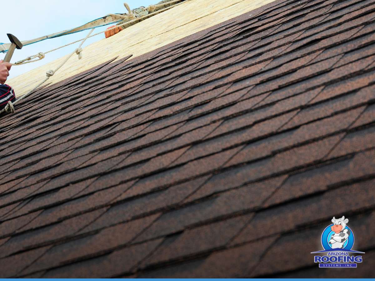 Roofing contractor installing synthetic roofing materials with a hammer
